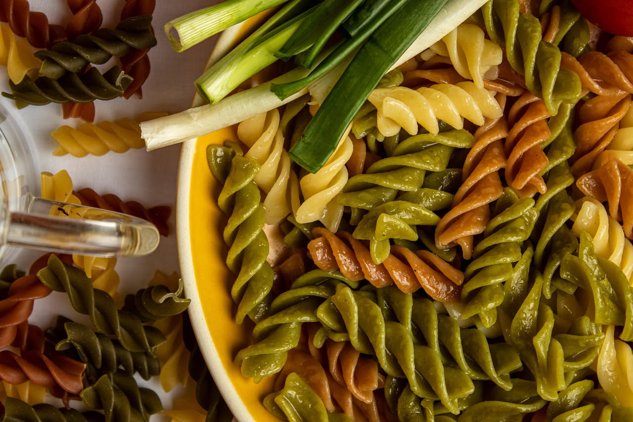 Piatto di fusilli con cozze in salsa di pomodoro: pasta rigatata avvolta con molluschi aperti e scuri, aglio soffritto, prezzemolo fresco spezzettato sulla superficie, servito in scodella bianca su ta