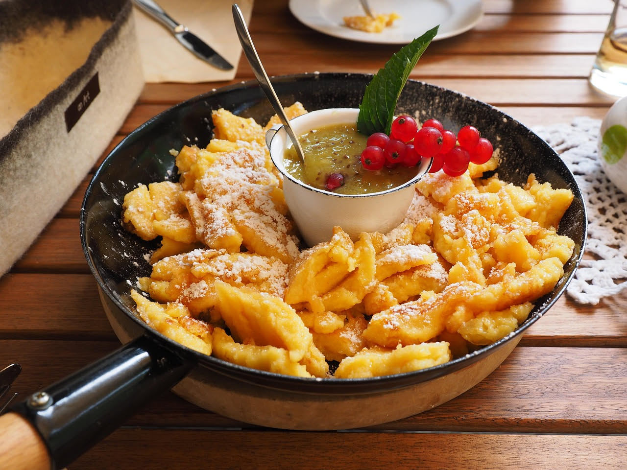 Gnocchetti di semolino gialli e leggermente rugosi nel piatto bianco, conditi con burro fuso e formaggio grattugiato, accompagnati da erba cipollina fresca e pepe nero