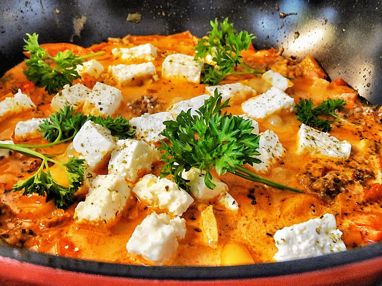 Gnocchi alla bergamasca nel piatto bianco, ricoperti di ragù marrone scuro, grana padano grattugiato in fili dorati, rosmarino fresco come guarnizione, su tavolo di legno naturale