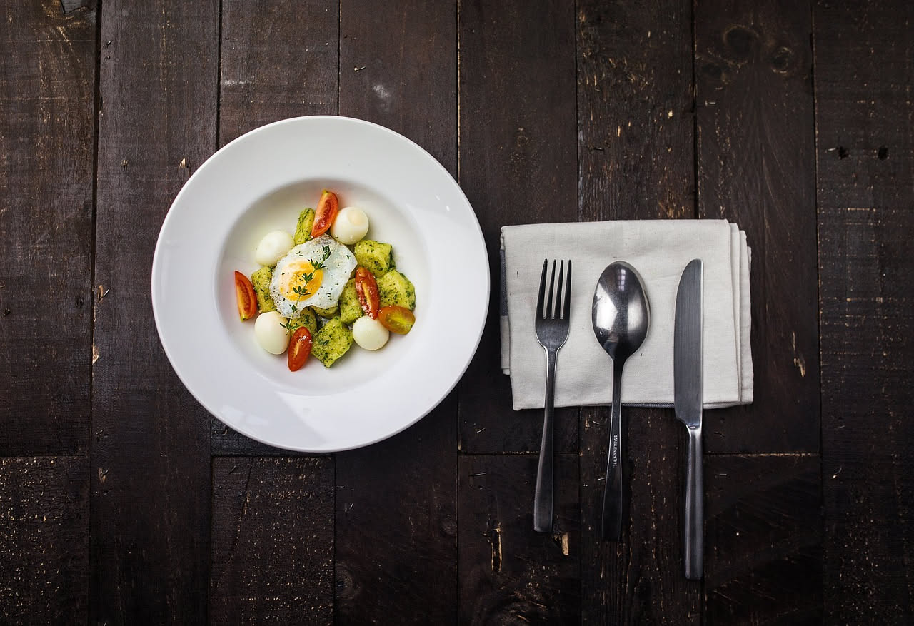 Gnocchi alla sorrentina appena sfornati, dorati in superficie, con mozzarella filante visibile tra gli gnocchi, salsa di pomodoro rosso vivo, gratinatura di parmigiano bianco, serviti in piatto bianco
