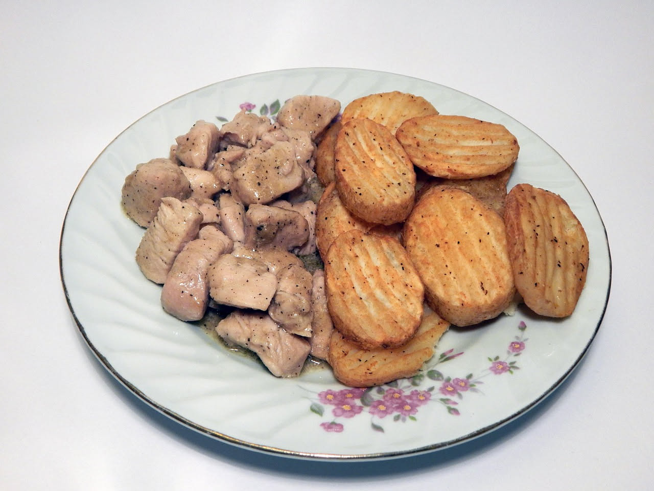 Piatto di gnocchi bianchi con salsa cremosa, conditi con tartufo nero grattugiato e prezzemolo, su piatto bianco lucido con bordo smerlato