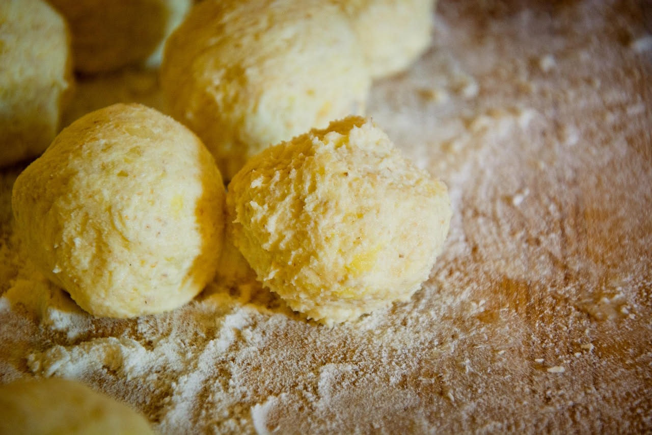 Gnocchi di semola fritti dorati e croccanti impilati su un piatto bianco, con una ciotola di salsa di pomodoro accanto