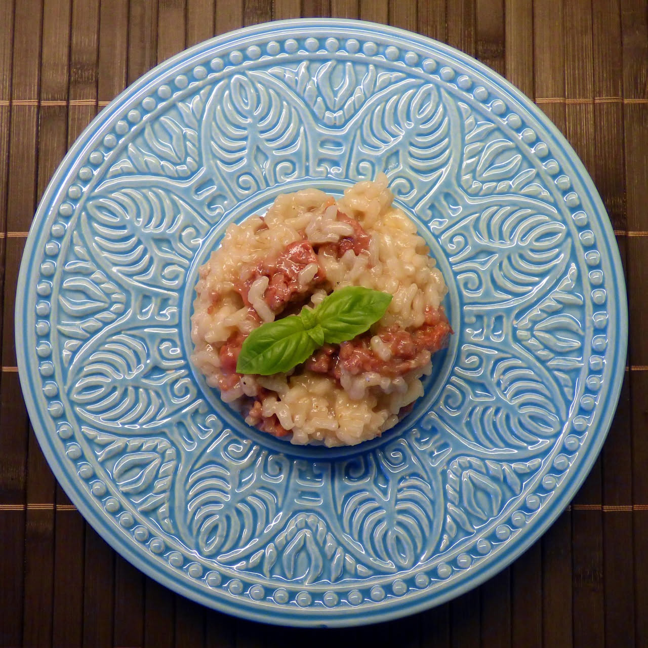 Piatto di risotto cremoso bianco e blu marmorizzato con cucchiaio di legno, fondo di lino grigio neutro