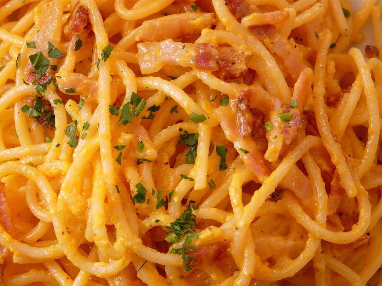 Fette sottili di guanciale molisano disposte a raggiera su un piatto bianco, con il colore rosa pallido e il grasso marezzato ben visibile, accompagnato da pane tostato sullo sfondo