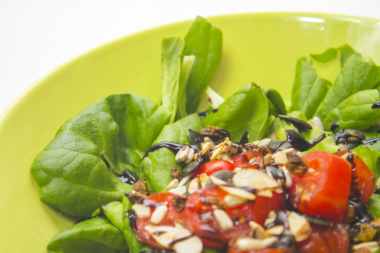 Insalata d'orzo in una ciotola bianca con chicchi di orzo, pomodori rossi tagliati, cetrioli verdi, cipolla rossa e prezzemolo fresco sotto la luce naturale