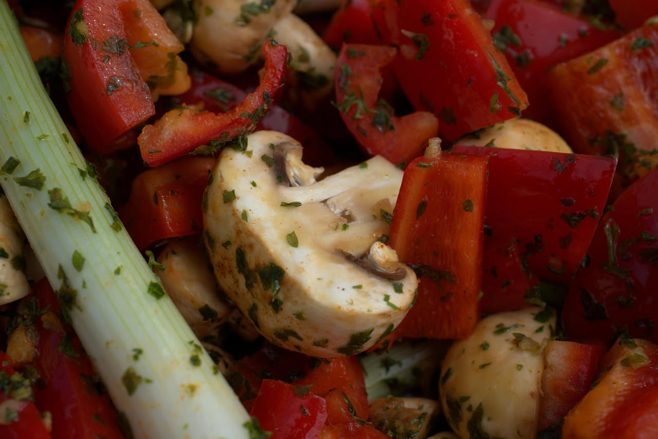 Insalata di funghi champignon e porcini affettati sottili su un piatto bianco, conditi con olio d'oliva, limone e prezzemolo fresco