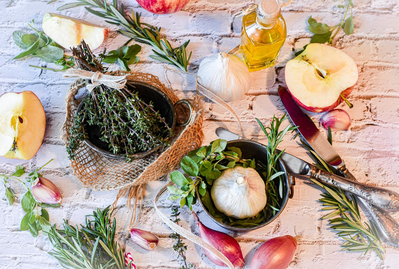 Lardo aromatico a fette, colore bianco avorio con striature rosa, adagiato su un piatto bianco, con rametti di rosmarino fresco e bacche di ginepro sparse intorno