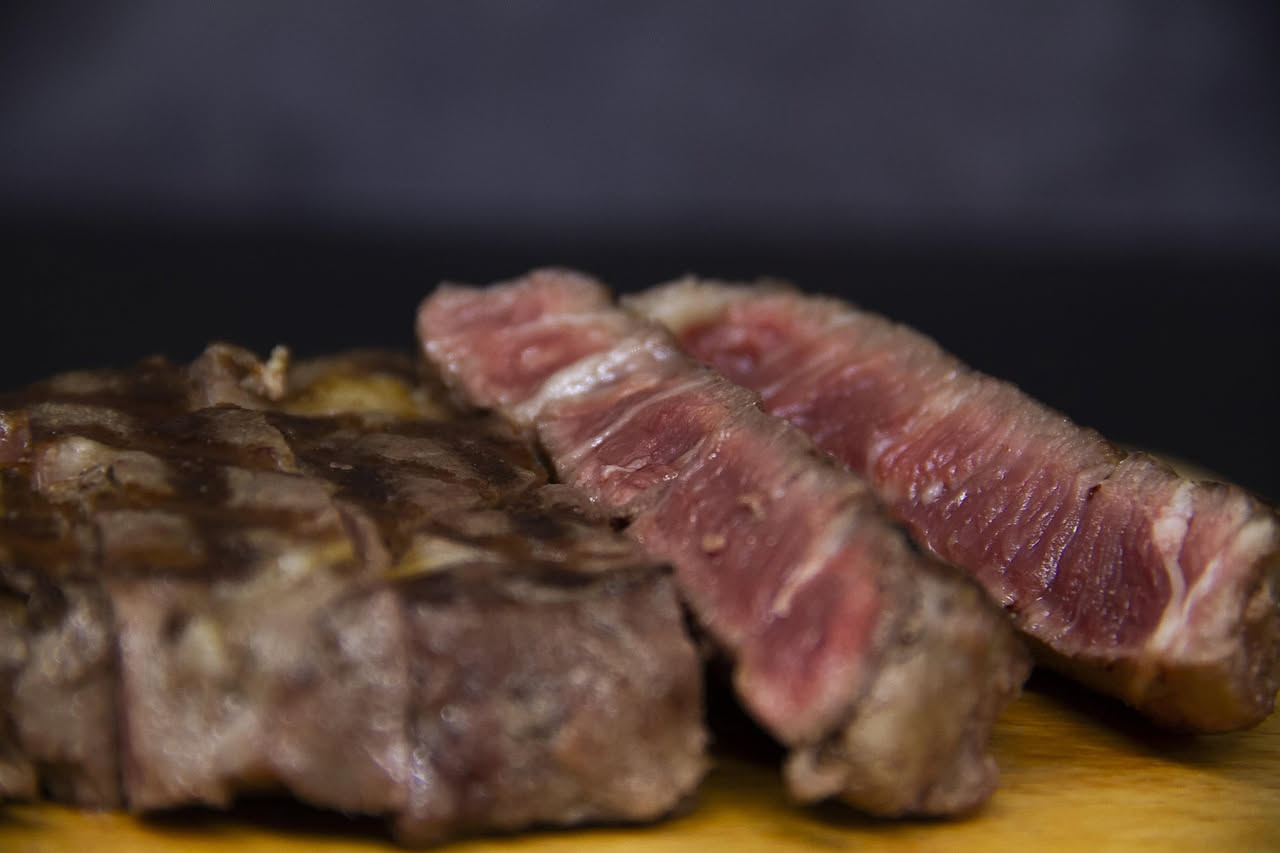 Lombata al barbecue sulla graticola incandescente, con crosticina marrone e striature di fuoco, accompagnata da fette di limone fresco e rosmarino aromatico sul piatto
