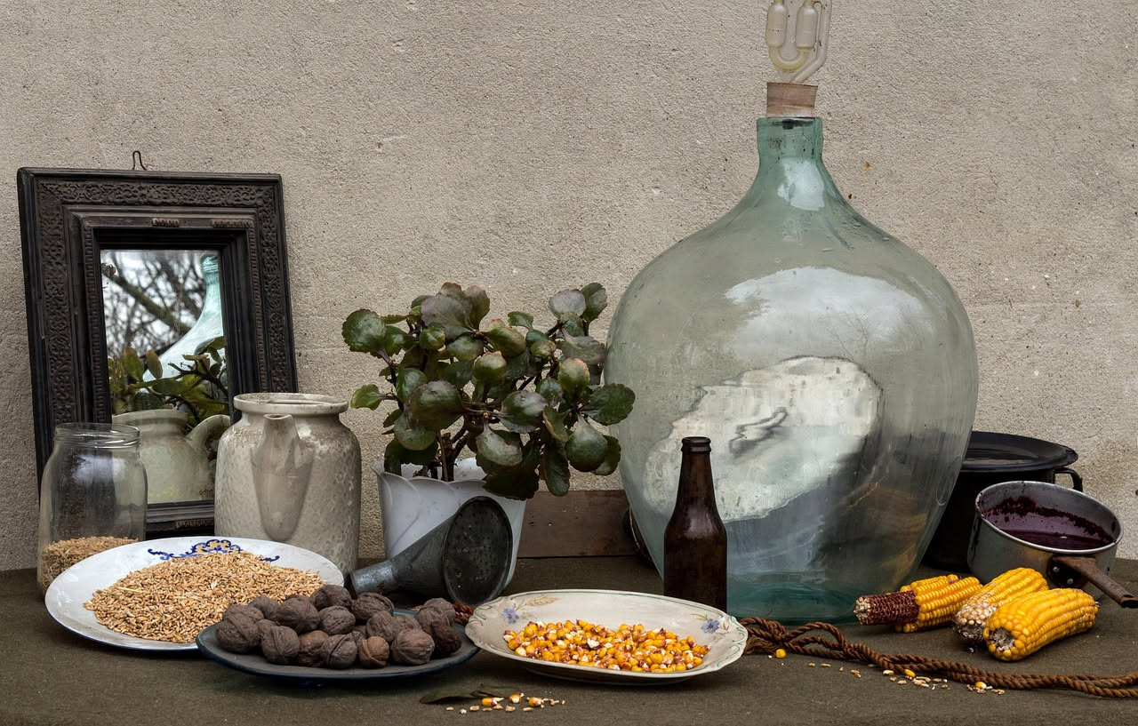 Ciotola di ceramica bianca con minestra di granoturco giallo e fagioli rossi in brodo trasparente, condita con olio verde, un giro di pepe nero e una foglia di prezzemolo fresco sul bordo