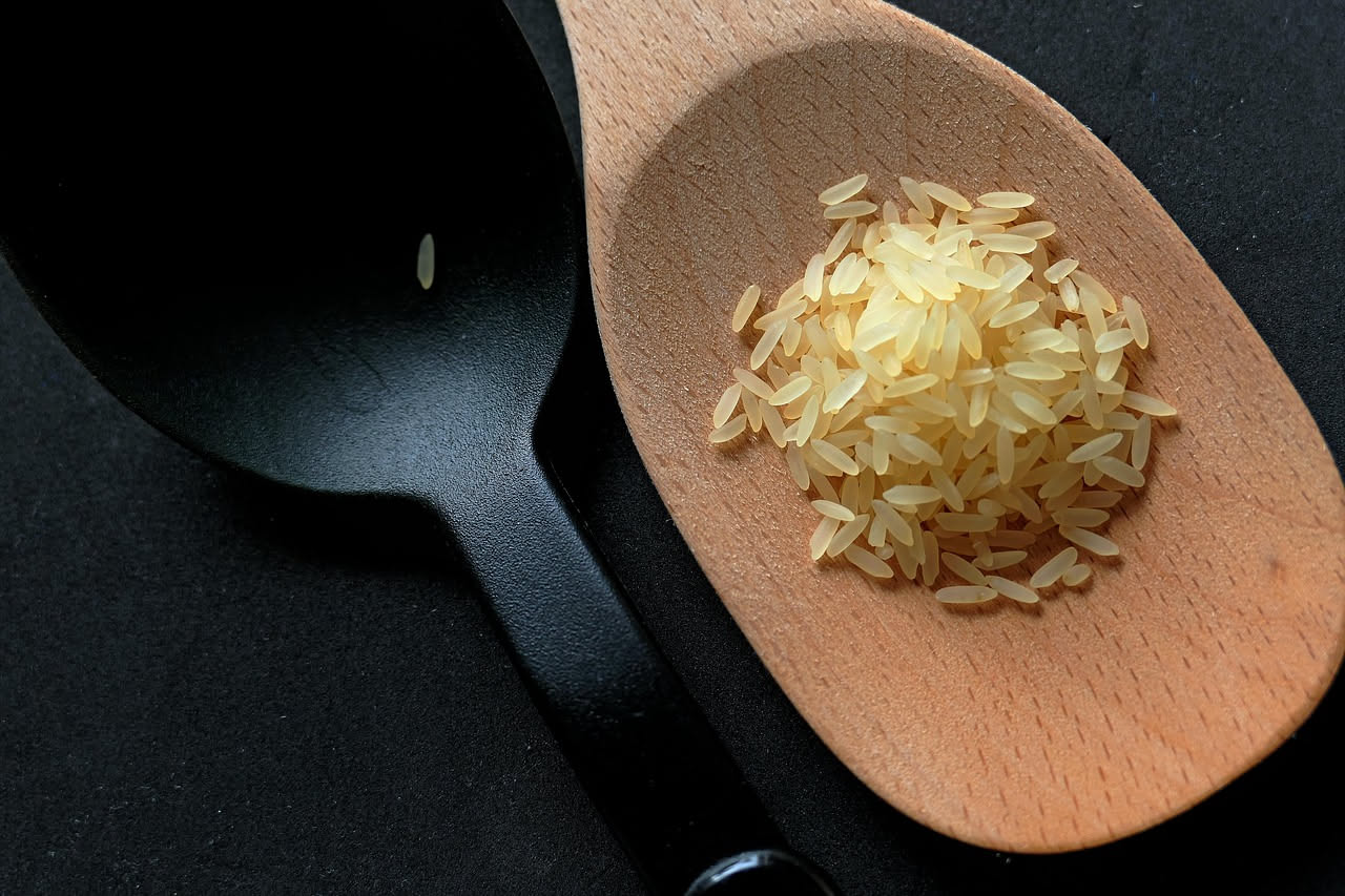 Minestra di riso e patate in una ciotola di ceramica bianca, con chicchi di riso visibili, pezzetti di patata morbidi, brodo trasparente e leggermente cremoso, spolverata di prezzemolo fresco verde e