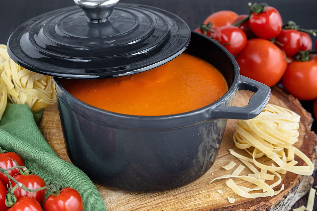 Una ciotola di minestra di soffritto con brodo ambrato, pezzetti di cipolla caramellata, sedano e carota morbidi, gocce di olio verde in superficie, pane tostato sul bordo, su tavolo di legno scuro
