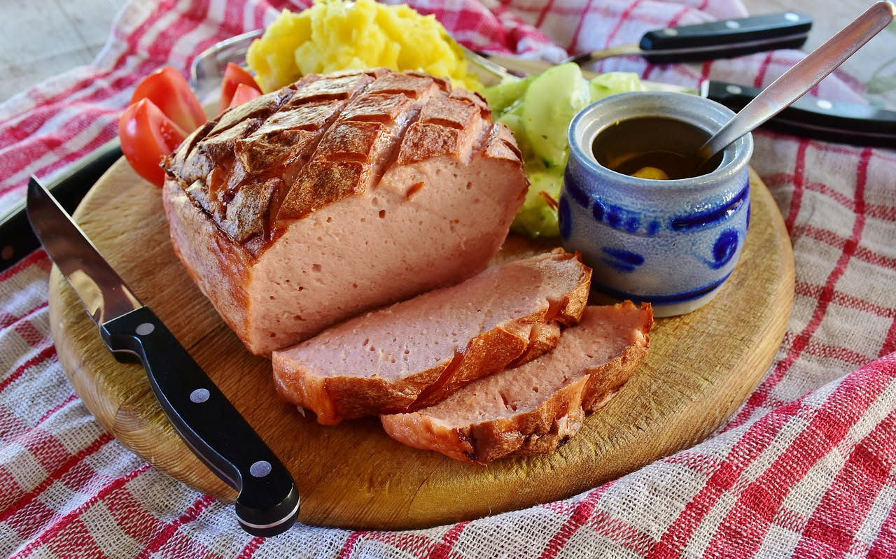 Fette di mortadella rosa pallido con cubetti di lardo bianco, tagliate nette su un piatto bianco, con pepe nero visibile