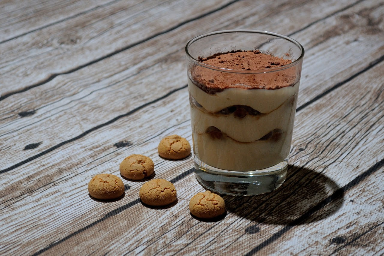 Musetto affettato su un piatto bianco, fette rotonde color marroncino-rosato con grana visibile, accanto purè di patate fumante e verza cotta, posto su tavolo di legno rustico