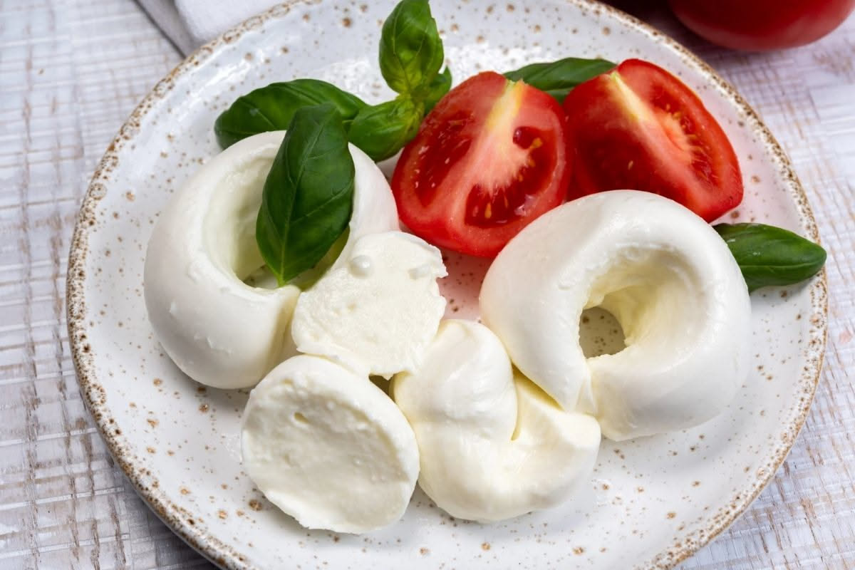 Nodini di mozzarella fritti su un piatto bianco, dorati e croccanti, con uno spicchio che mostra il formaggio filante all'interno