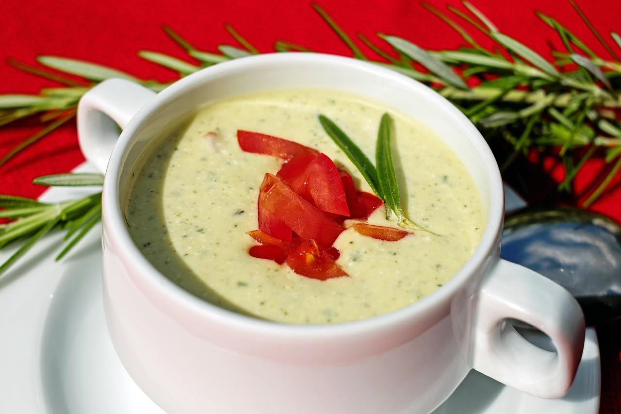 Scodella di ceramic bianca con panada cremosa giallo-dorata, guarnita con prezzemolo fresco verde e filo d'olio al centro, su tovaglia di lino beige