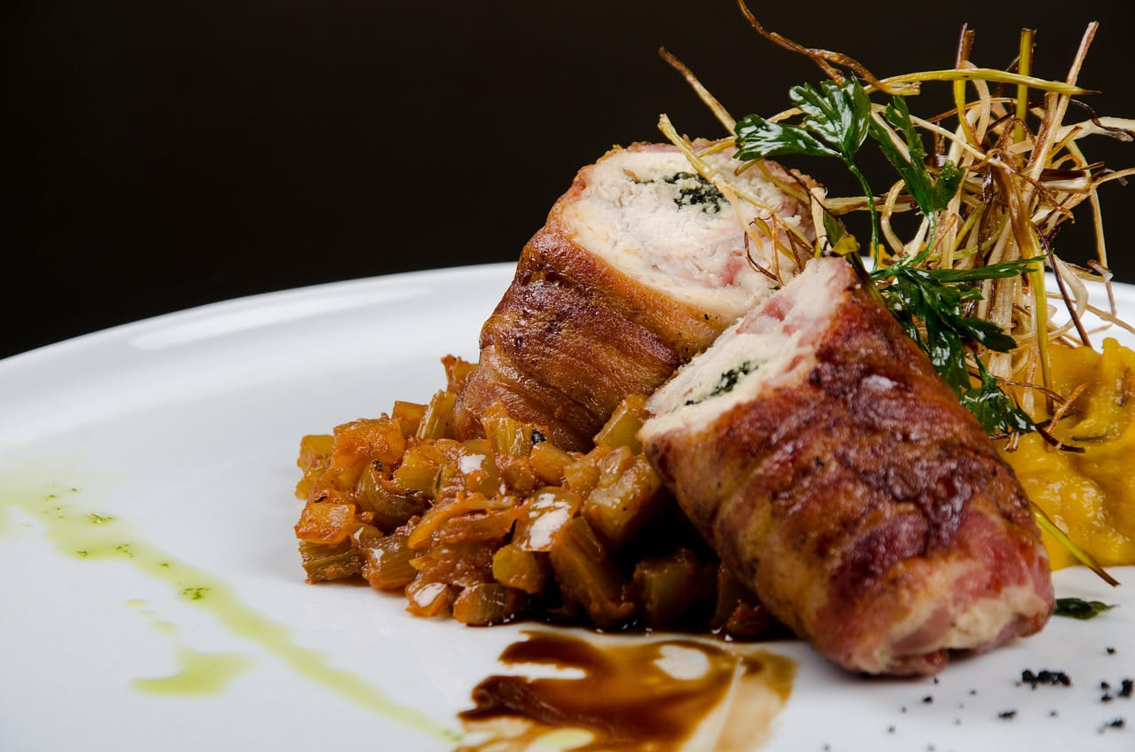 Pancetta arrotolata croccante e dorata in una padella di ghisa con bordi bruniti e grasso trasparente attorno