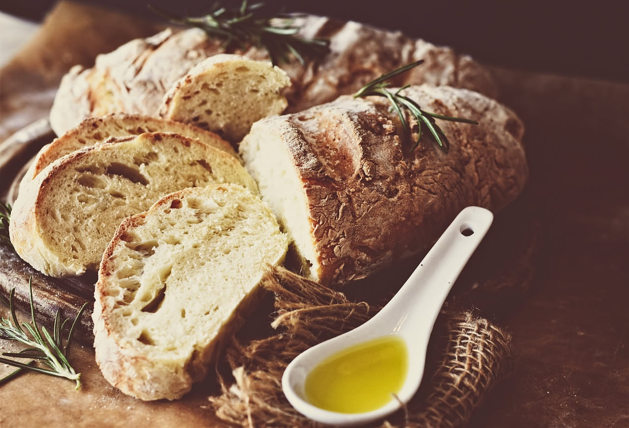 Fette di pane tostato dorate su un piatto bianco, condite con olio extravergine che forma gocce lucide e sale grosso sparso in superficie