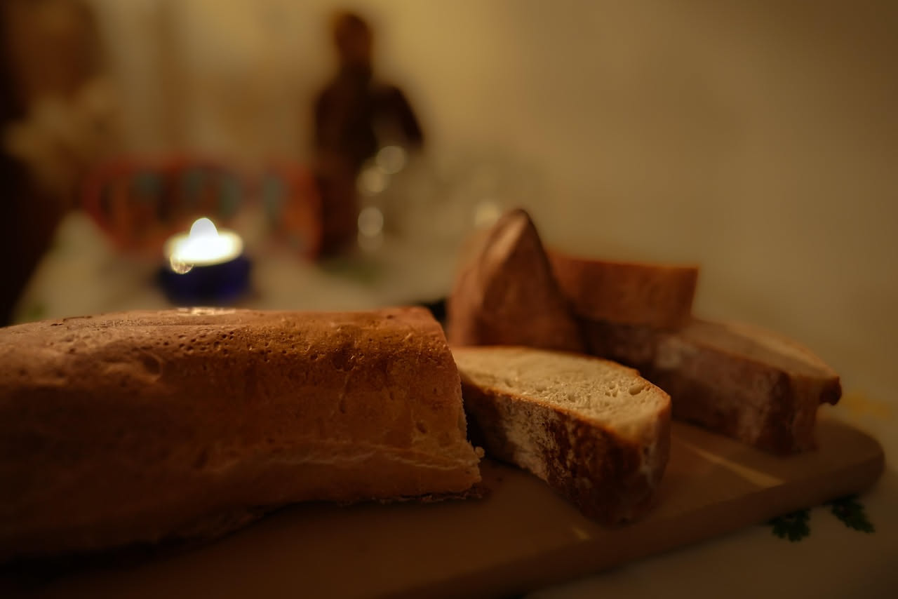 Un piatto bianco con due fette di pane tostato dal colore dorato, coperte da fette sottili di salam rosso scuro leggermente arricciate, accompagnate da pomodoro fresco affettato e foglie di basilico v