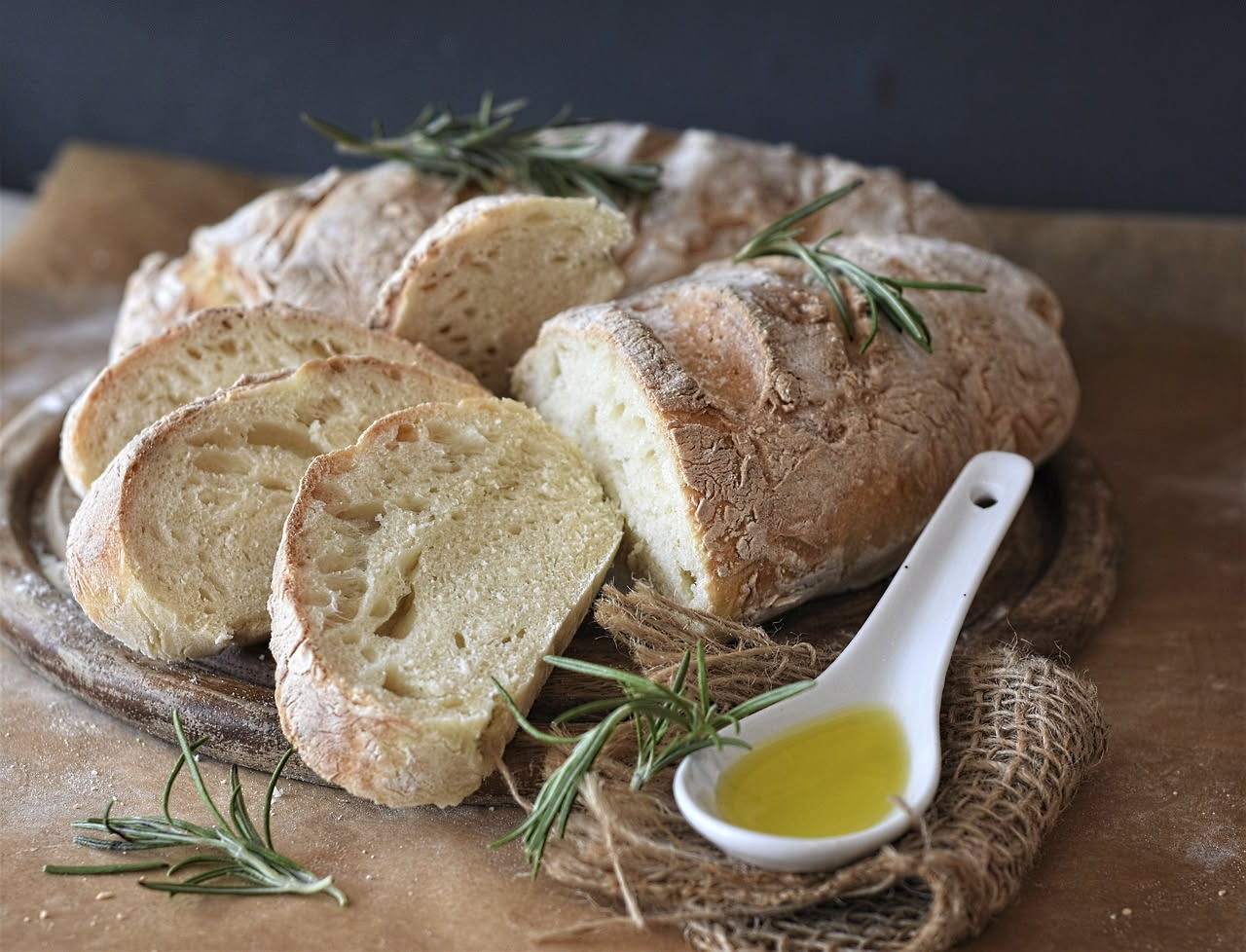 Pane toscano tagliato a fette, cosparso d'olio d'oliva, su un piano di legno con una bottiglia di olio accanto