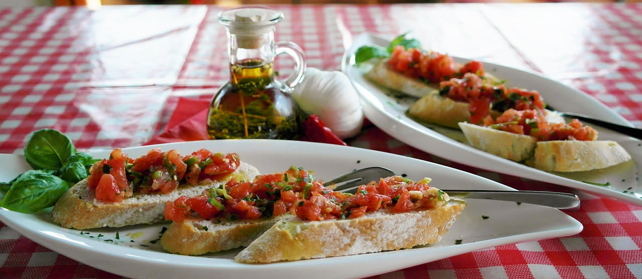 Fette di pane tostato dorate in un piatto bianco, cosparse di olio di oliva verde, con qualche goccia lucida sulla superficie
