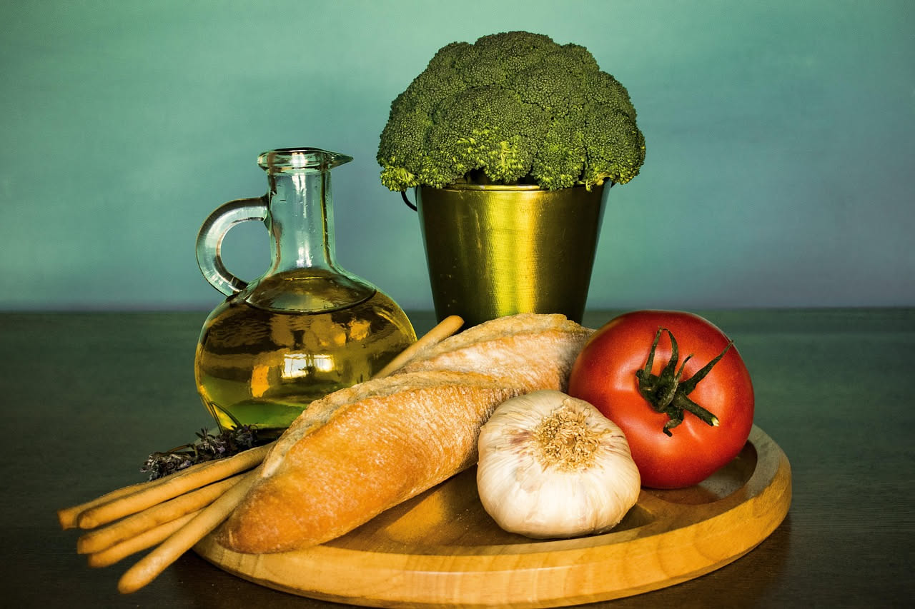 Fette di pane tostato color dorato, bagnate generosamente di olio verde scuro, con grani di sale marino grosso visibili sulla superficie, disposte su un piatto bianco. Un rametto di rosmarino fresco a