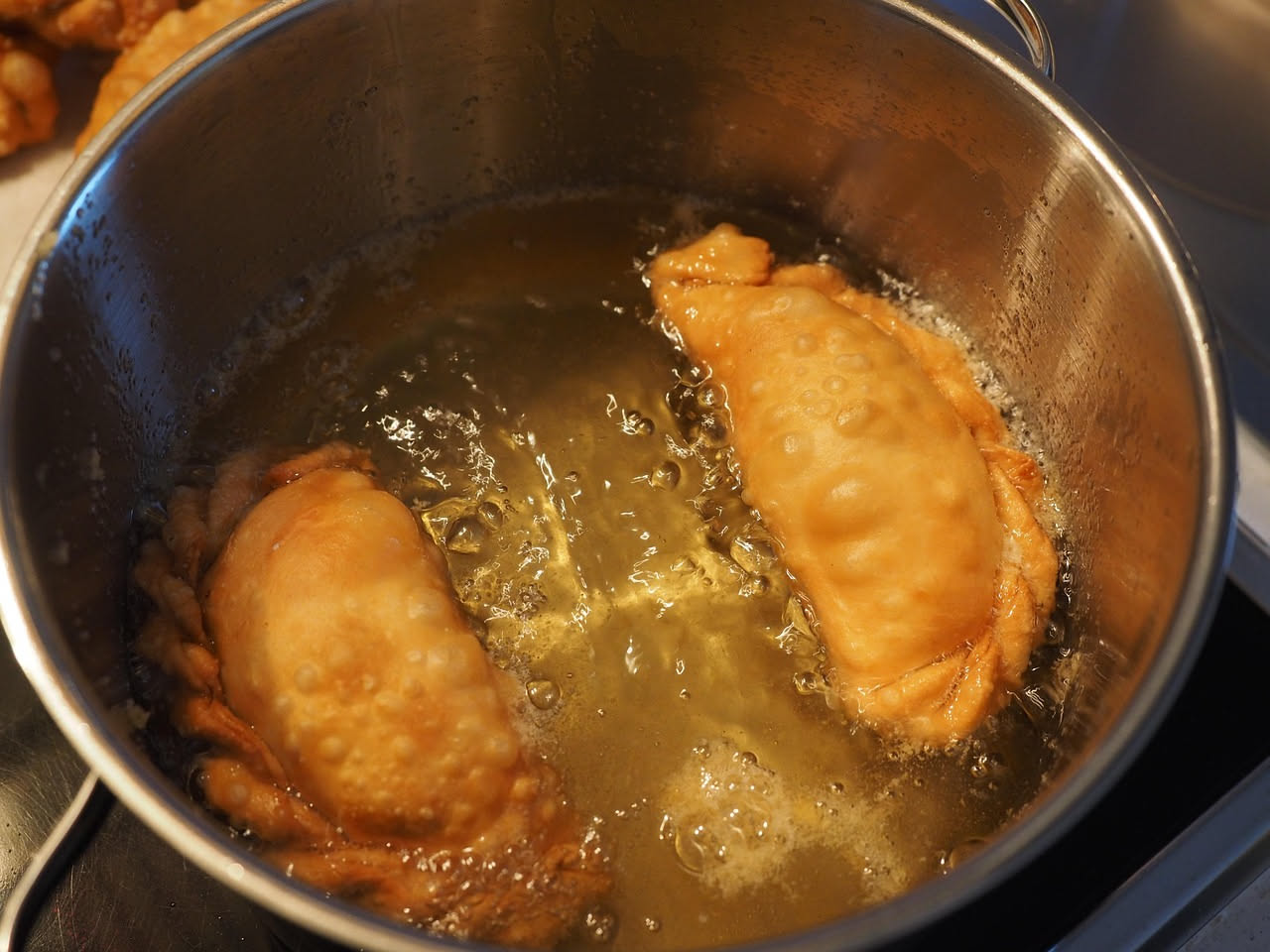 Panzerotti fritti dorati disposti su un piatto bianco, ancora fumanti, con dentro visibile il ripieno di mozzarella filante e pomodoro rosso. Superficie croccante e lucida, impiattamento spartano.