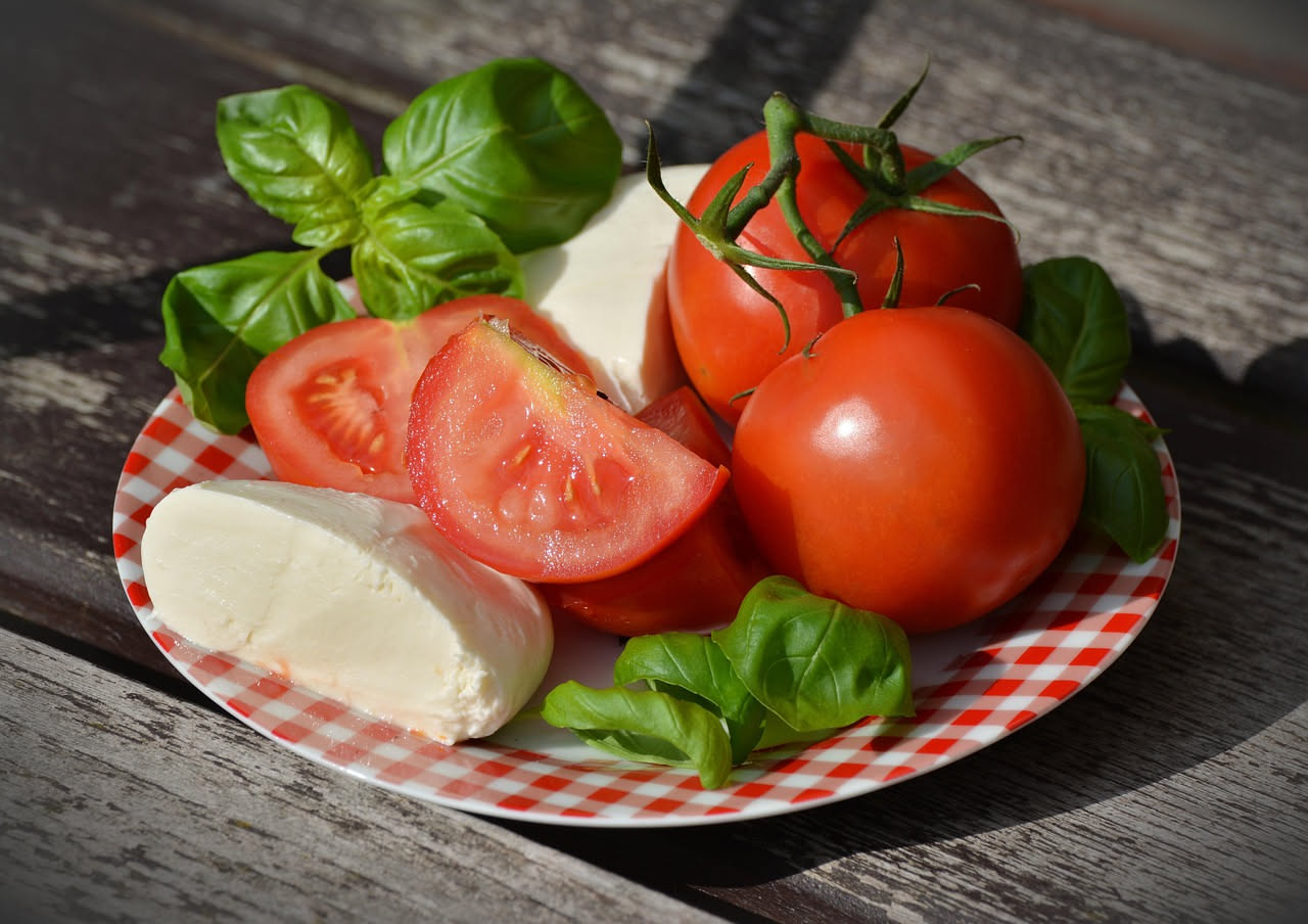 Ciotola di pappa al pomodoro parmigiana color rosso-arancio, cremosa, con scaglie di parmigiano dorato in superficie e filo d'olio extravergine, contorno di pane tostato