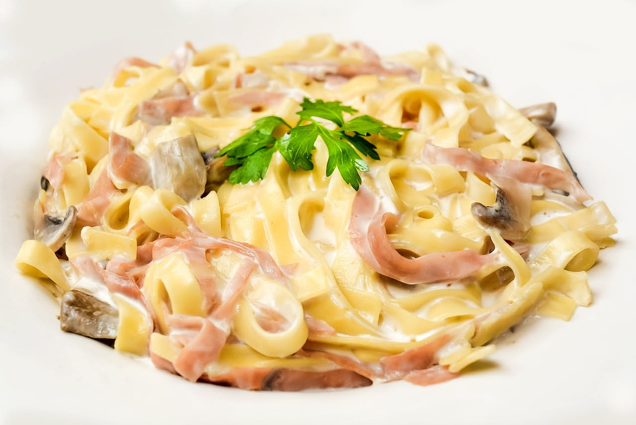 Piatto di pasta all'agrigentina servito in una ciotola bianca, con filamenti dorati di zafferano, sardine grigie e finocchio verde distribuiti sulla pasta, condita con olio d'oliva lucido