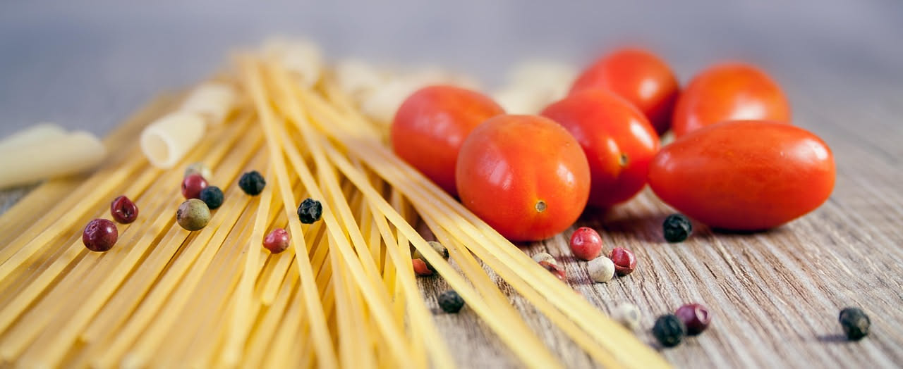 Piatto di pasta alla scarpariello con spaghetti ricoperti di olio lucido, pezzetti visibili di aglio dorato, peperoncino rosso e prezzemolo verde sparso in superficie, servito in piatto bianco su tavo