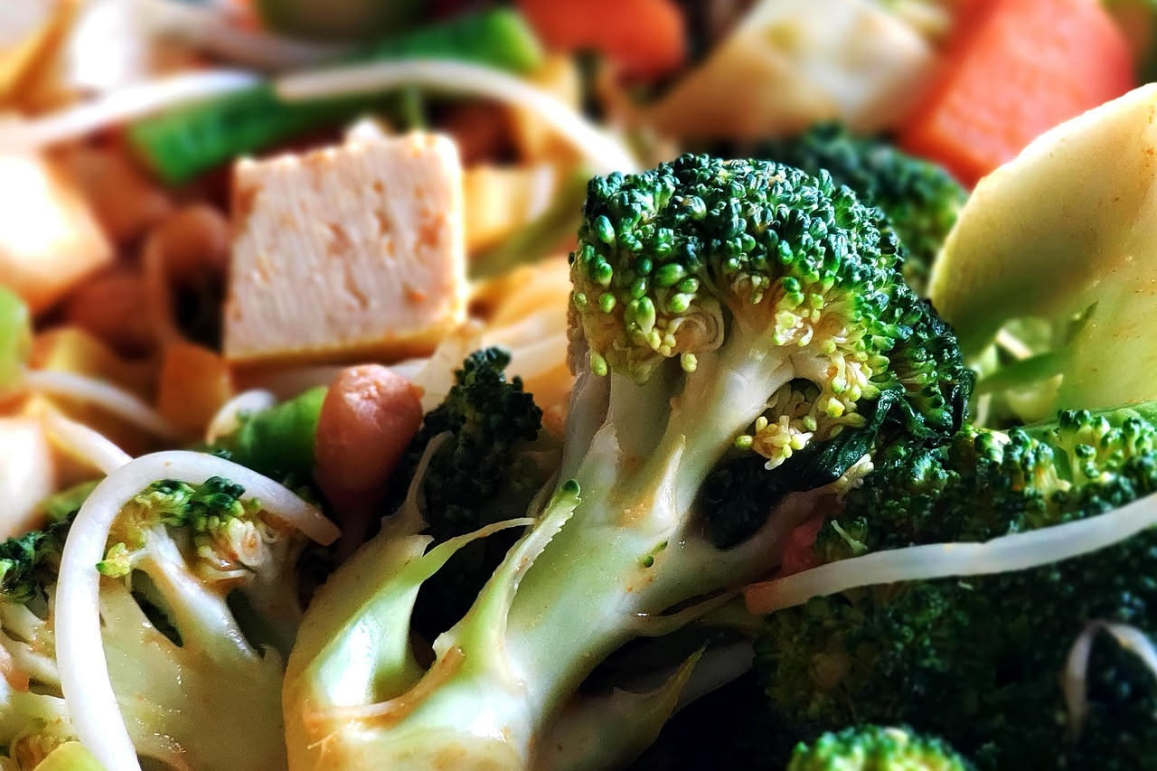 Piatto di pasta con broccoli verdi e acciughe salate, olio d'oliva e aglio dorato, servito in una ciotola bianca con foglie di prezzemolo fresco