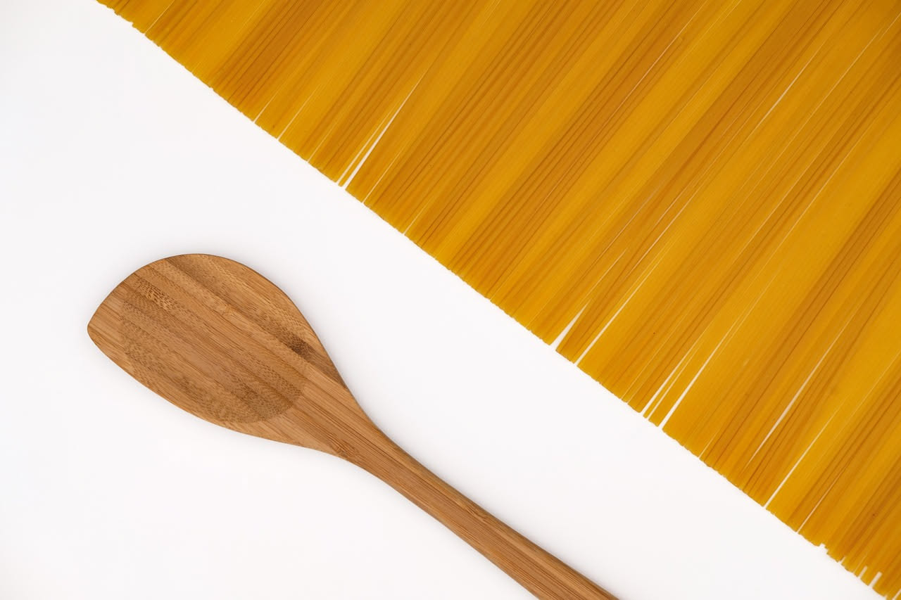 Piatto di spaghetti con bottarga grattugiata color ambra dorato su pasta cremosa al burro, con gocce d'olio d'oliva e pepe nero macinato al momento, servito in una ciotola bianca profonda su tavolo di