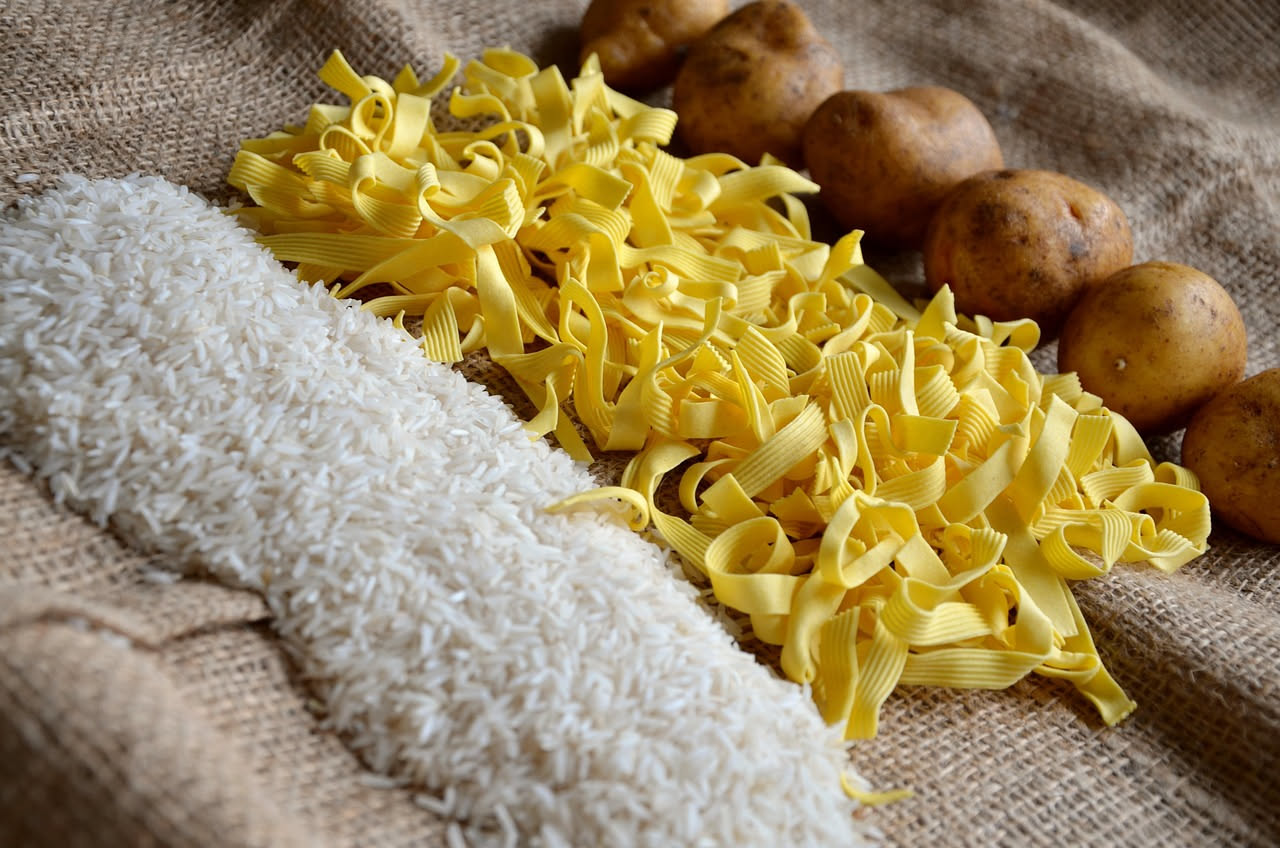 Piatto di ceramica bianca con pasta e patate in brodo caldo fumante, patate gialle tagliate a cubetti, rifinito con olio d'oliva e prezzemolo fresco