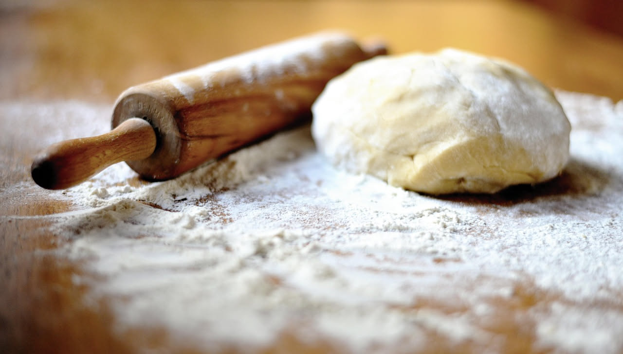 Strisce di pasta matta dorate e croccanti servite su piatto bianco, con bordi sfumati color nocciola, alcune leggermente piegate, spolverizzate di zucchero fine