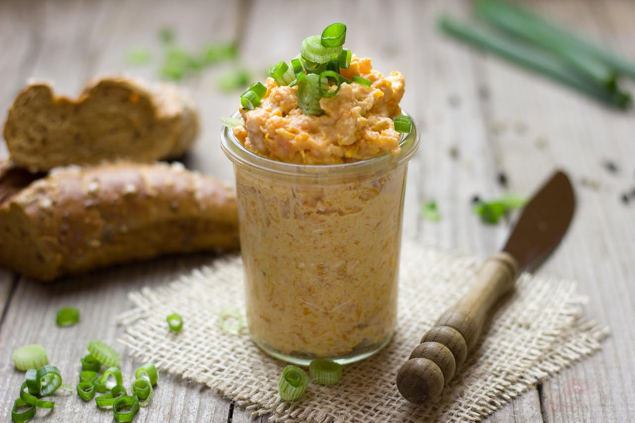 Patè di tonno cremoso in una ciotola bianca, guarnito con prezzemolo fresco e limone affettato, con crostini di pane tostato accanto