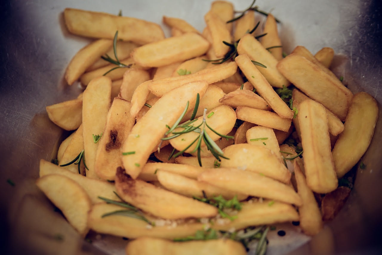 Patatine fritte dorate e croccanti in una ciotola bianca con sale grosso, sfondo neutro