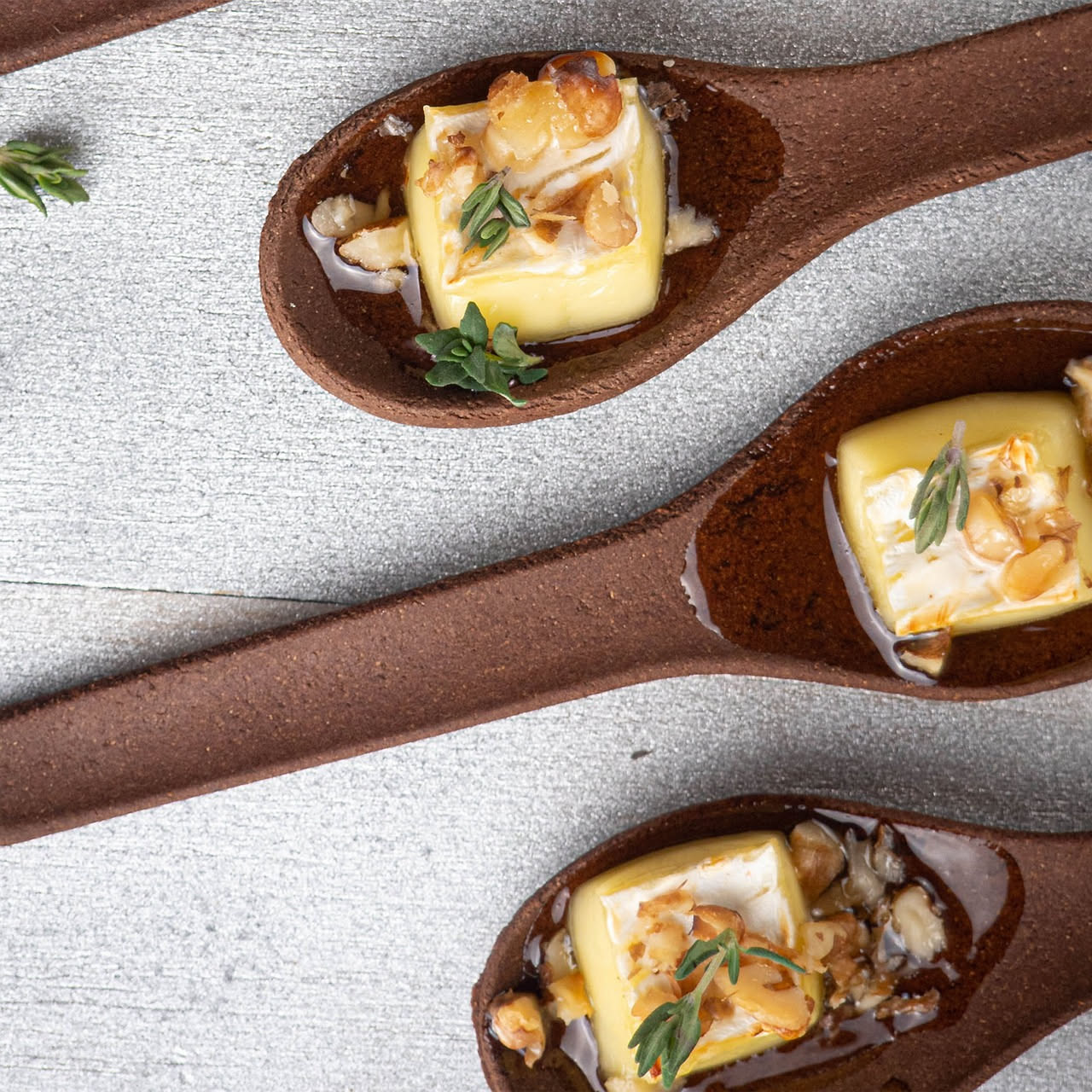 Piatto bianco con cubetti di pecorino fresco bianco latte, filo di miele ambrato che drizza verso l'alto, qualche goccia ancora fresca, sfondo grigio neutro