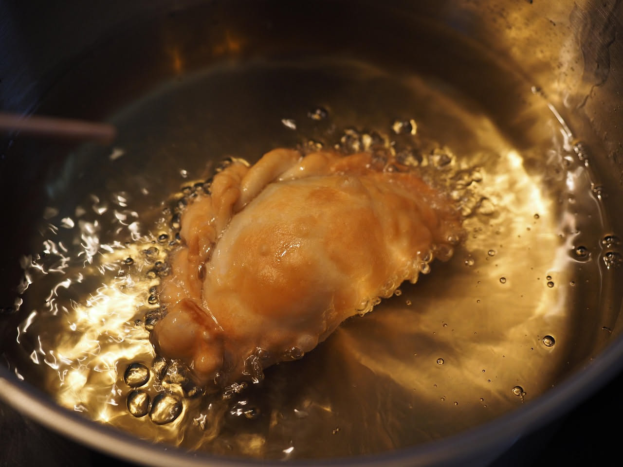 Pirichittas dorate e croccanti in un piatto bianco, acciliate di olio, con una leggera doratura uniforme e forma irregolare tondeggiante