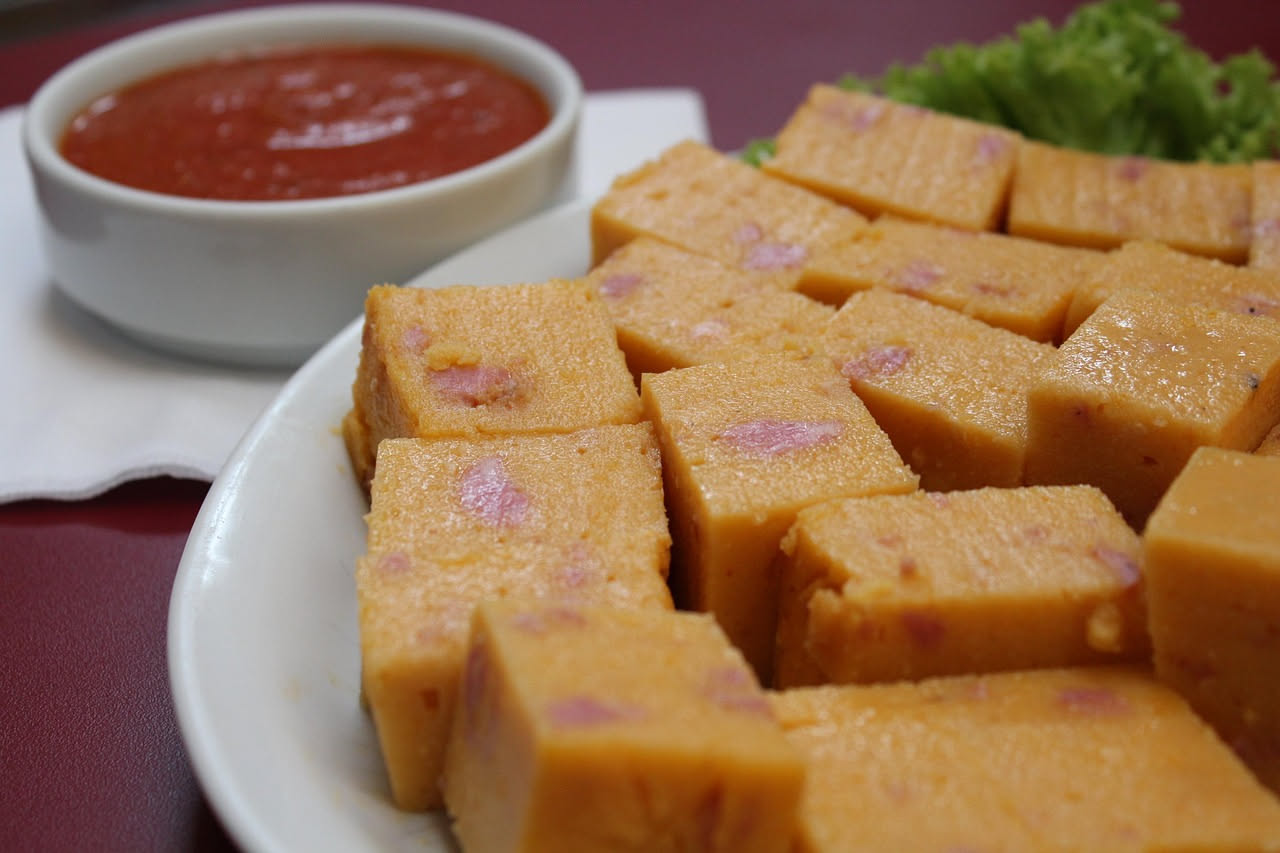 Piatto di polenta cremosa giallo dorato con tre formaggi fusi che si sciolgono in fili bianchi sulla superficie, guarnita con pepe nero macinato fresco e una noce di burro nel centro, servita in un pi