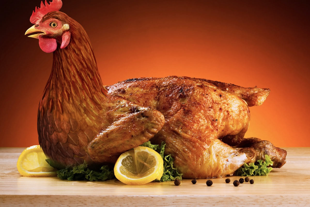 Pollo intero dorato al forno su un piatto bianco, tagliato a metà per mostrare il ripieno di verdure verdi e pane tostato, circondato da insalata fresca e fette di limone