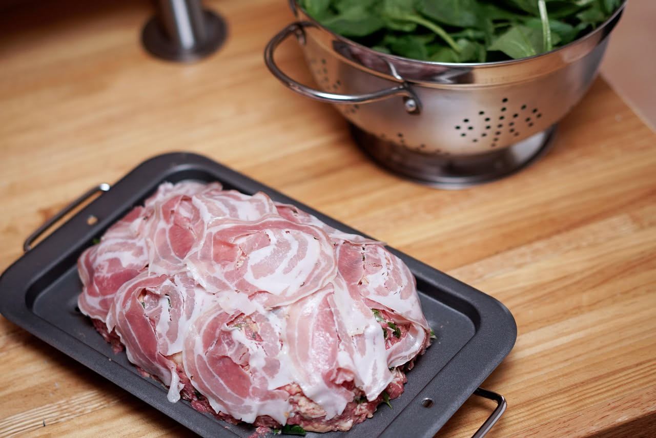 Porchetta dorata e croccante affettata su un tagliere di legno, con pelle brunita croccante ben visibile, contorno di fette di pane tostato e rametti di rosmarino fresco