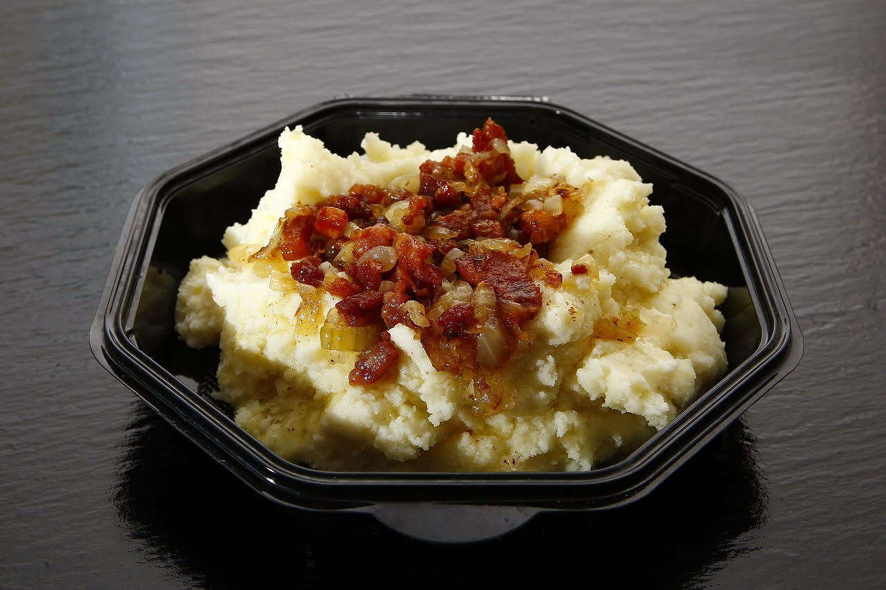 Piatto di fave verdi tenere e cipolle dorate caramellate in una ciotola di ceramica bianca, servito con pane tostato ai bordi e prezzemolo fresco tritato sopra