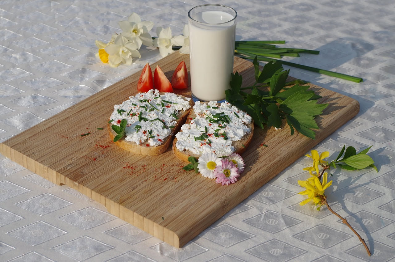 Raviggiolo bianco cremoso in una ciotola di terracotta, con accanto un cucchiaio di legno e foglie di menta fresca su un tavolo di legno naturale