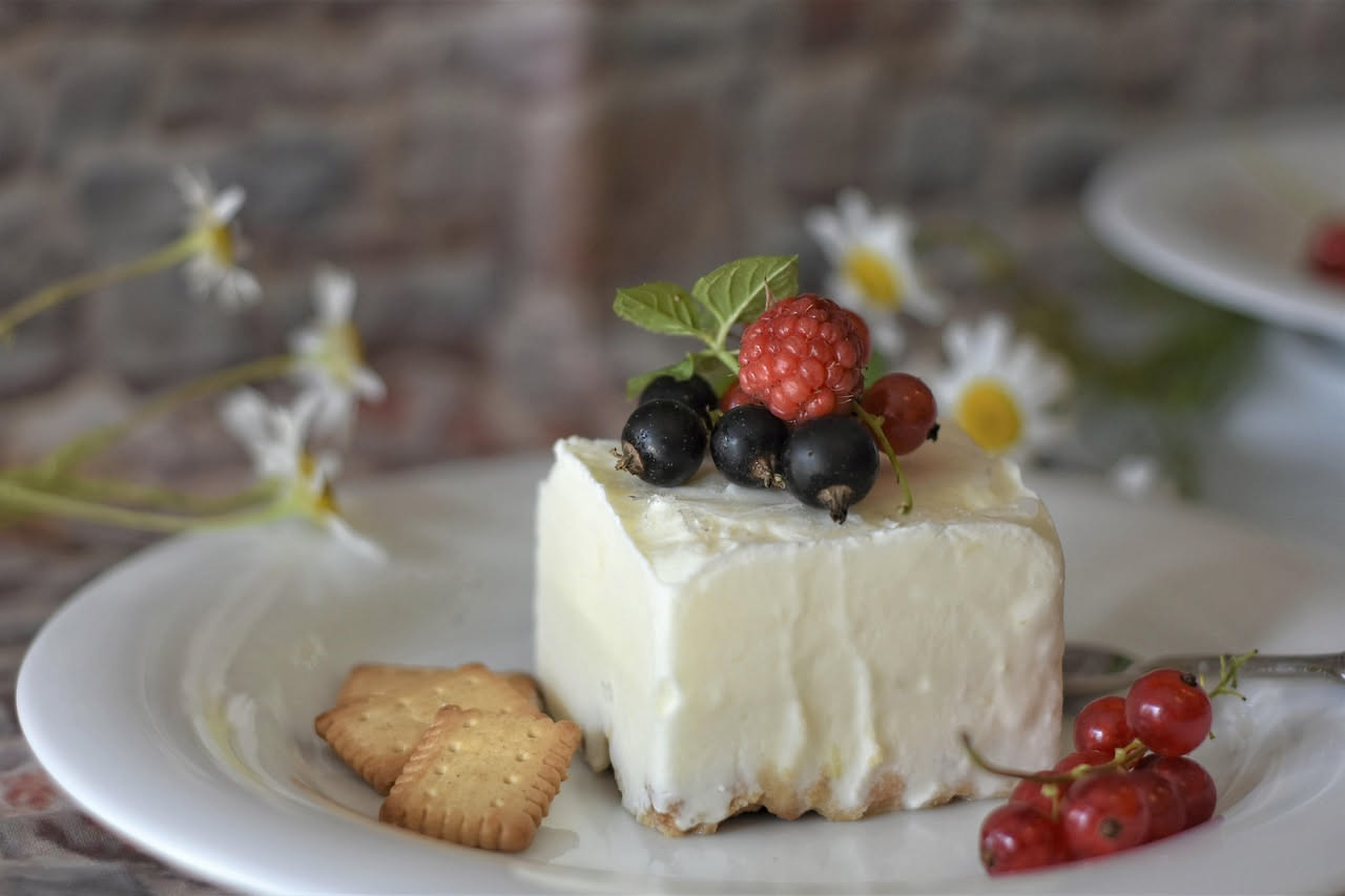 Ciotola di ricotta di bufala bianca cremosa con un cucchiaio di legno, accanto erbette fresche e miele colato sulla superficie