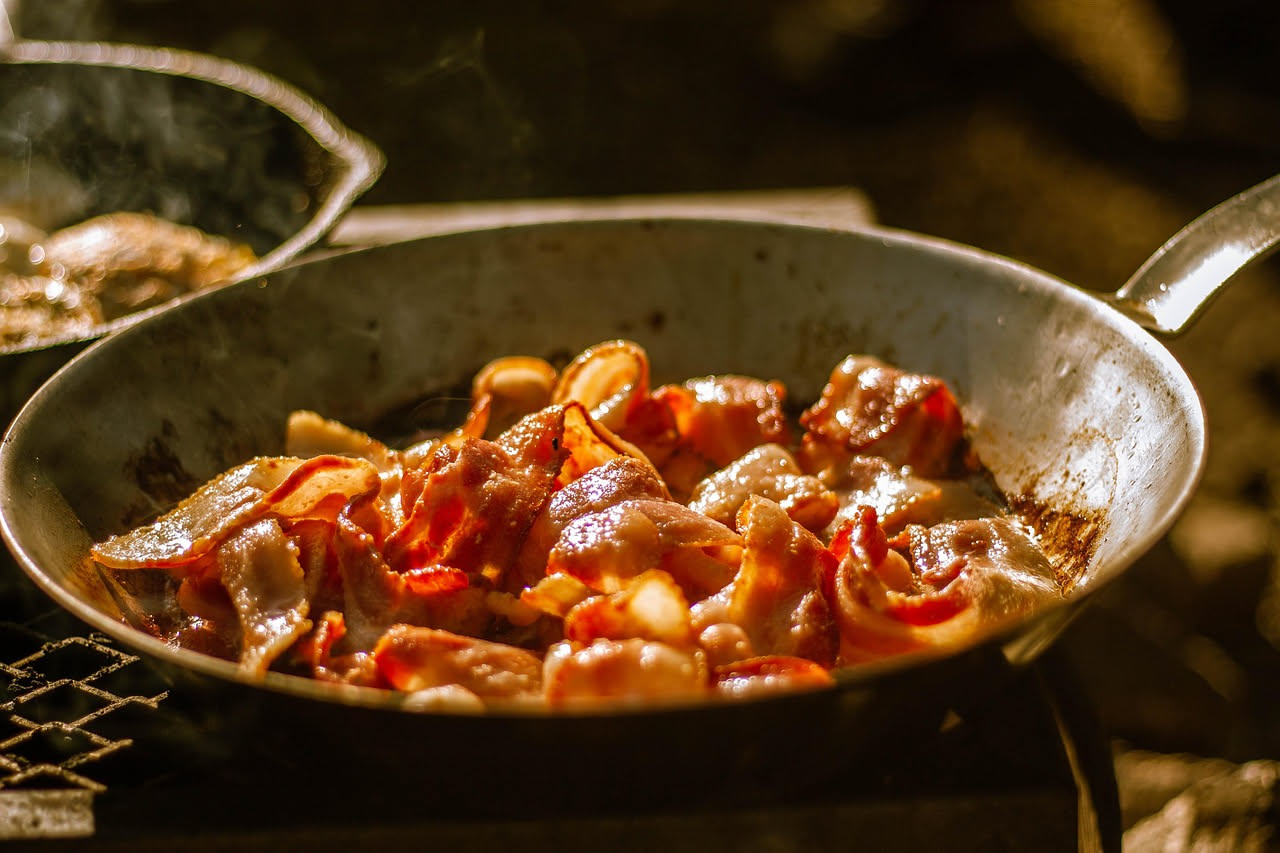 Fette di rigatino affumicato color marrone dorato con bordi croccanti poggiate su una carta bianca, con grani di sale grosso e rosmarino secco visibili