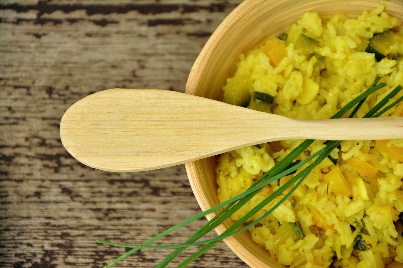 Piatto di riso alla trapanese servito in una ciotola bianca, riso mantecato di colore verde pallido con visibili granelli di riso separati, scaglie di mandorla sparse in superficie, qualche pezzetto d