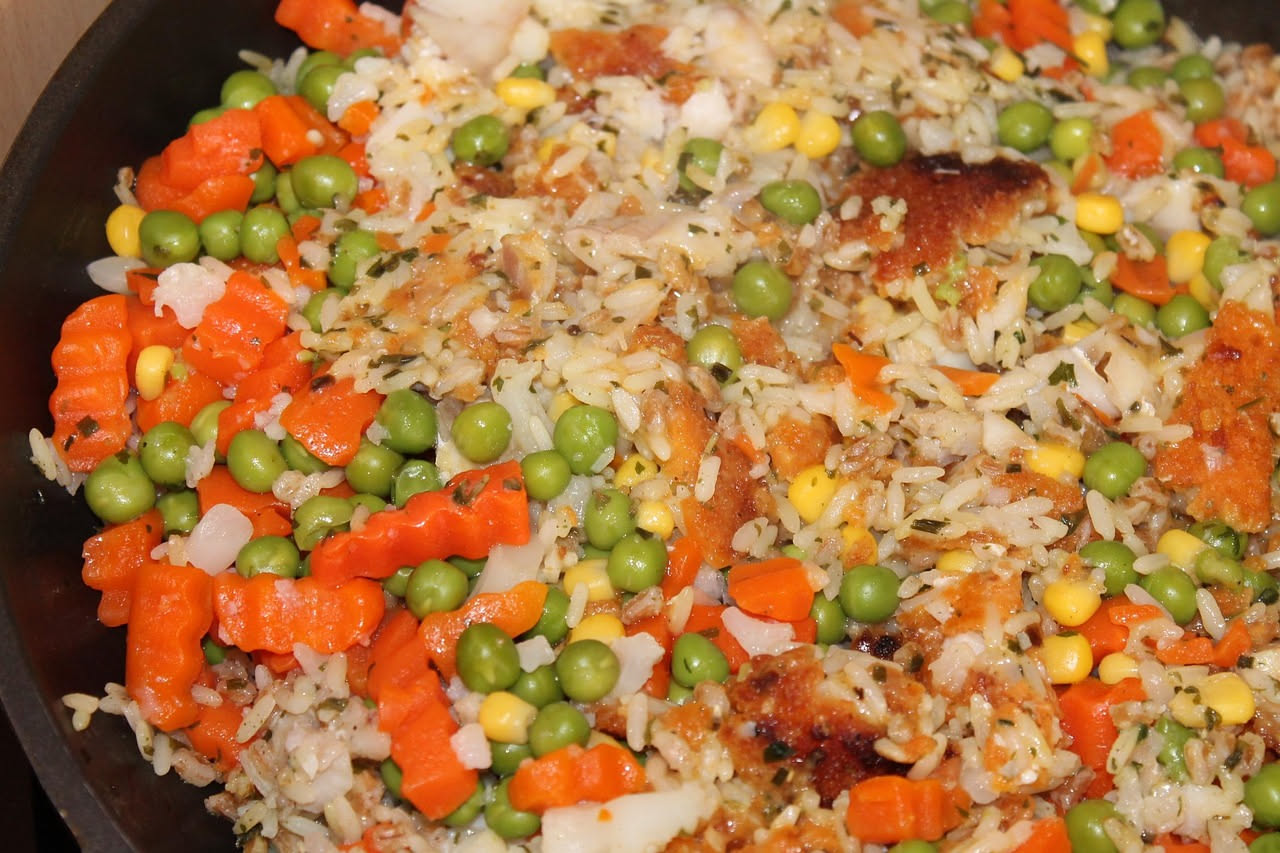 Piatto di riso e bisi servito in ciotola bianca: riso cremoso di colore bianco con piselli verdi brillanti sparsi in superficie, gocce di brodo visibile, guarnizione di prezzemolo fresco tritato sulla