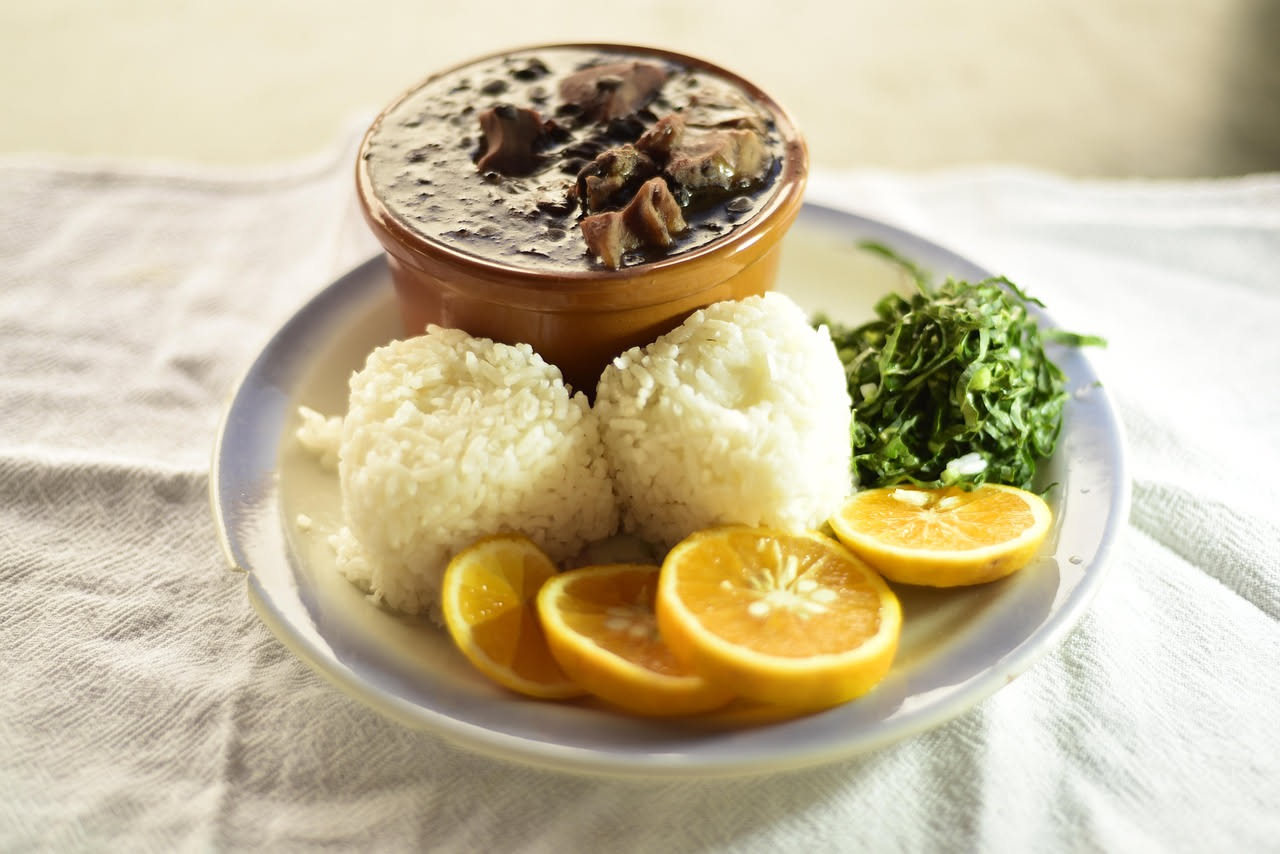 Un piatto fondo di riso bianco cremoso con pezzi di luganega marrone dorato e rosso, caldo appena uscito dal fuoco, con un filo d'olio in superficie e raso di parmigiano