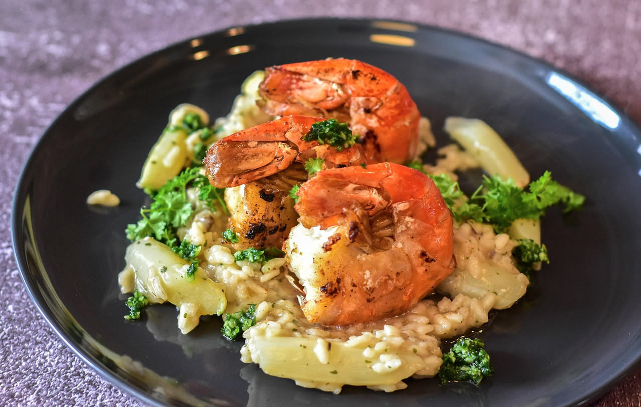Risotto alla romagnola in piatto bianco: riso cremoso di colore beige-marrone con ragù di carne visibile, guarnito con parmigiano grattugiato e un filo d'olio, su fondo neutro