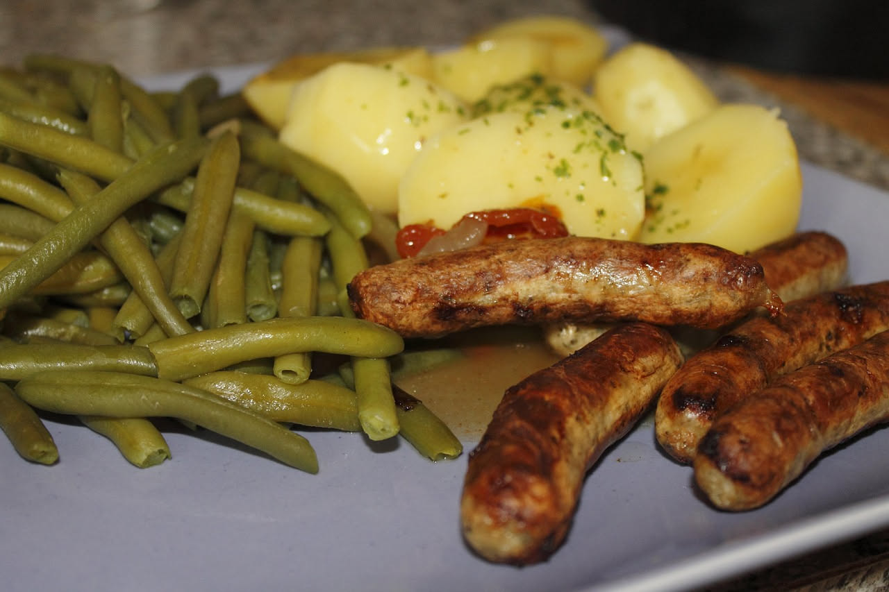 Salsiccia di fegato affettata su un tagliere di legno, di colore marrone scuro, accompagnata da fette di pane tostato e una rametto di rosmarino fresco