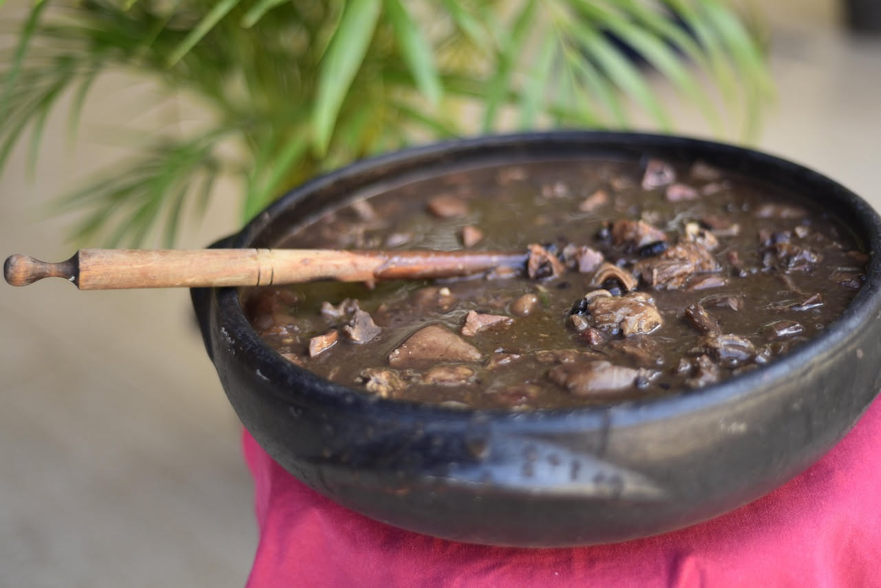 Sangue di maiale cotto affettato su un piatto bianco, dalla forma regolare e il colore bruno scuro, accompagnato da contorno di verdure saltate e prezzemolo fresco tritato